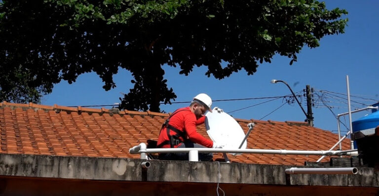 Técnico instala parabólcia digital em telhado.
